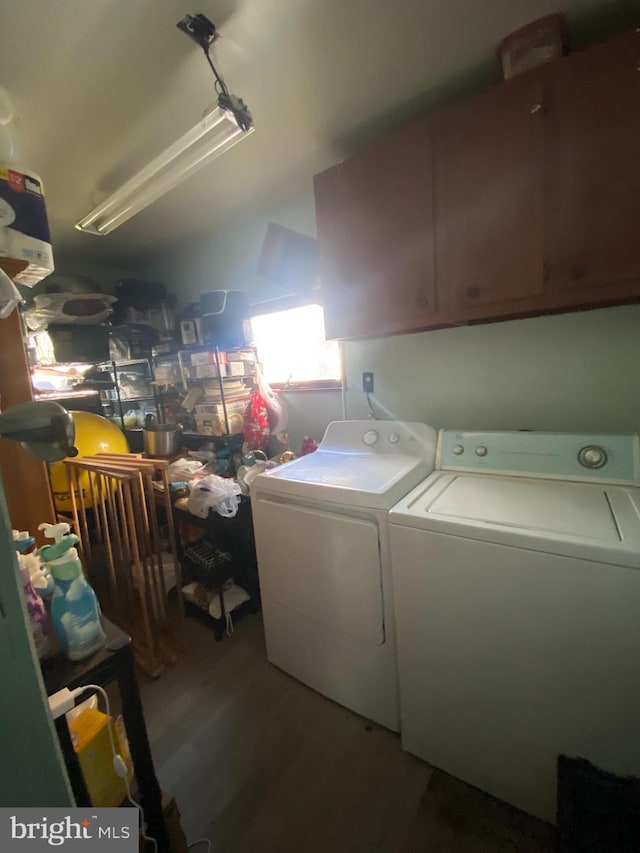 laundry room with cabinets, wood-type flooring, and washing machine and clothes dryer