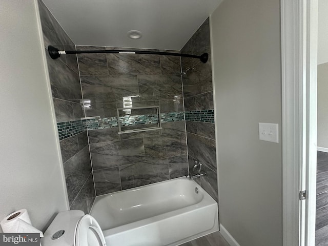 bathroom with tiled shower / bath, hardwood / wood-style floors, and toilet