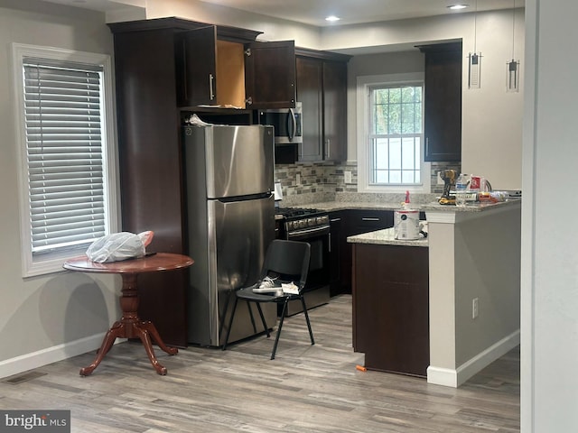 kitchen featuring light stone counters, stainless steel appliances, light hardwood / wood-style floors, and tasteful backsplash