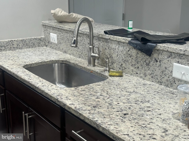 interior details featuring light stone countertops, dark brown cabinets, backsplash, and sink