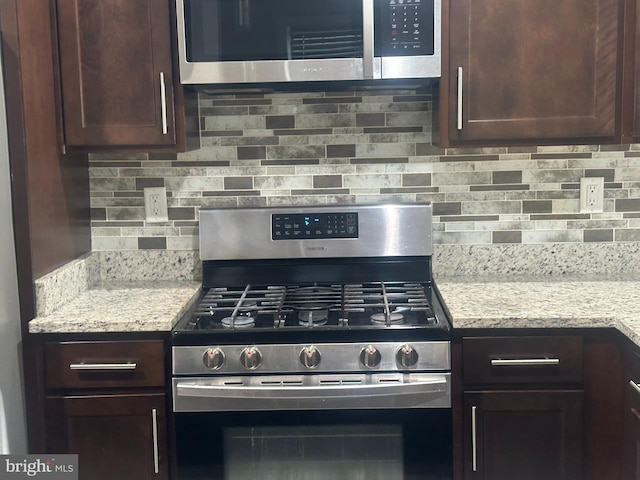 kitchen featuring decorative backsplash, stainless steel appliances, dark brown cabinets, and light stone countertops