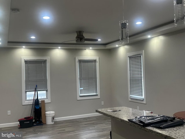 home office with a tray ceiling, ceiling fan, and hardwood / wood-style floors