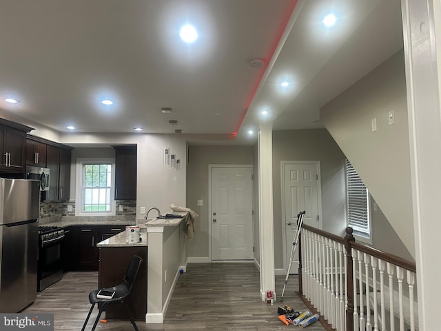 kitchen with light stone countertops, stainless steel appliances, dark hardwood / wood-style flooring, and a kitchen breakfast bar