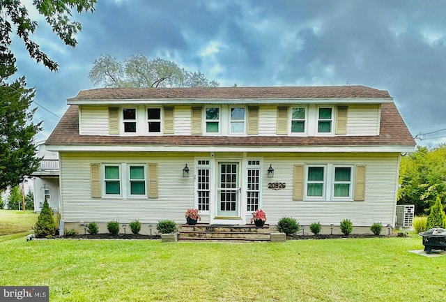 rear view of house featuring a fire pit, central air condition unit, and a lawn