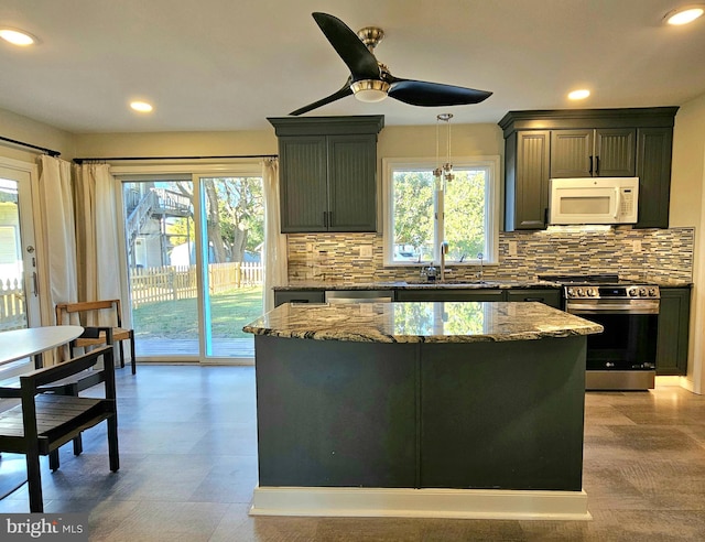 kitchen with a healthy amount of sunlight, appliances with stainless steel finishes, a kitchen island, and stone counters