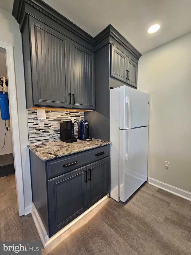 kitchen with backsplash, gray cabinets, stone counters, and white fridge