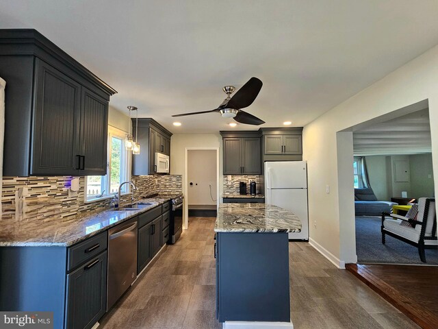 kitchen featuring pendant lighting, sink, backsplash, stainless steel appliances, and a center island