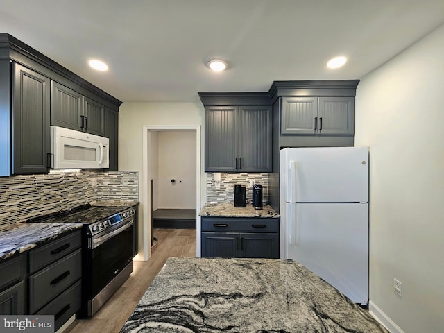 kitchen featuring stone countertops, backsplash, white appliances, and light wood-type flooring