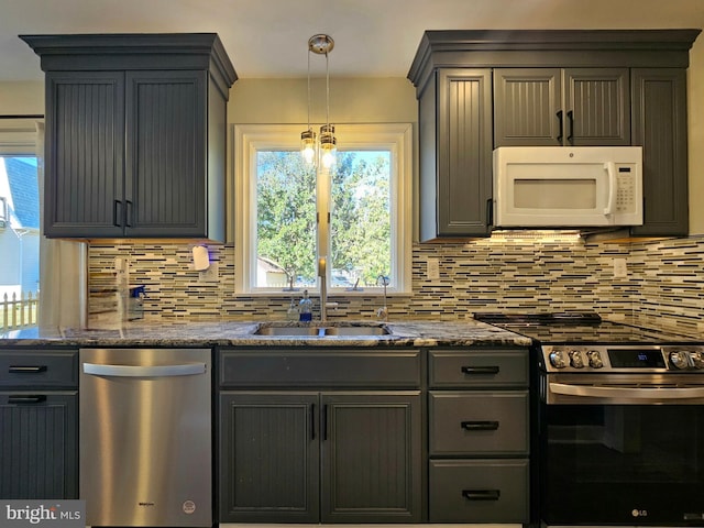 kitchen with tasteful backsplash, stainless steel appliances, decorative light fixtures, and sink