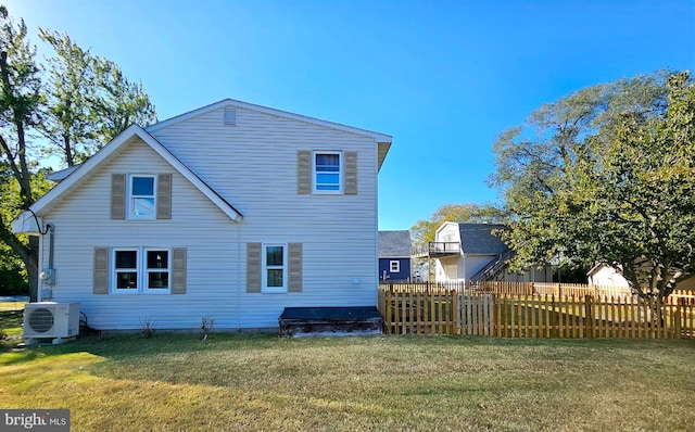 back of property with ac unit and a lawn