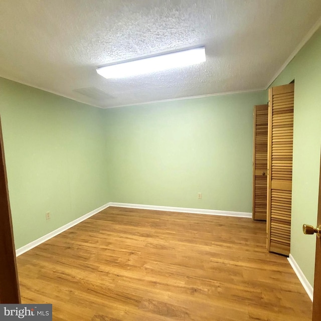 spare room featuring light hardwood / wood-style floors and a textured ceiling