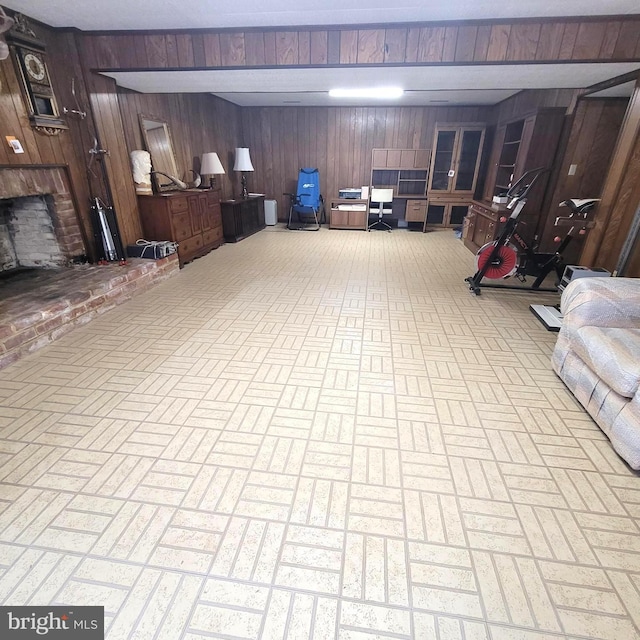 basement featuring wooden walls and a brick fireplace