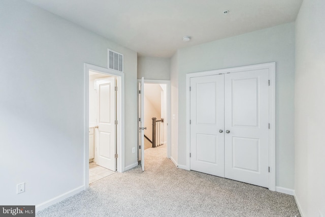 unfurnished bedroom featuring light carpet and a closet