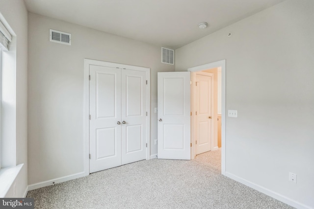 unfurnished bedroom with a closet and light colored carpet