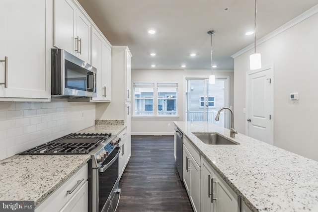 kitchen featuring stainless steel appliances, hanging light fixtures, sink, and white cabinetry