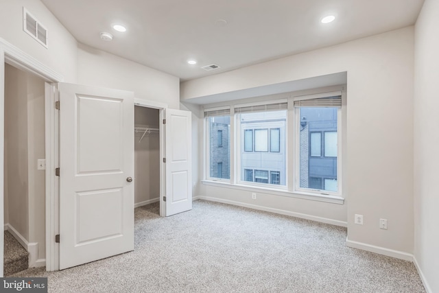 unfurnished bedroom with light colored carpet and a closet