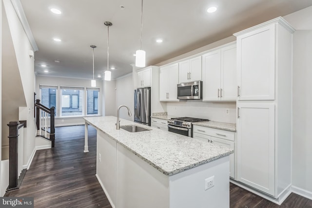 kitchen with decorative light fixtures, a kitchen island with sink, appliances with stainless steel finishes, and white cabinetry