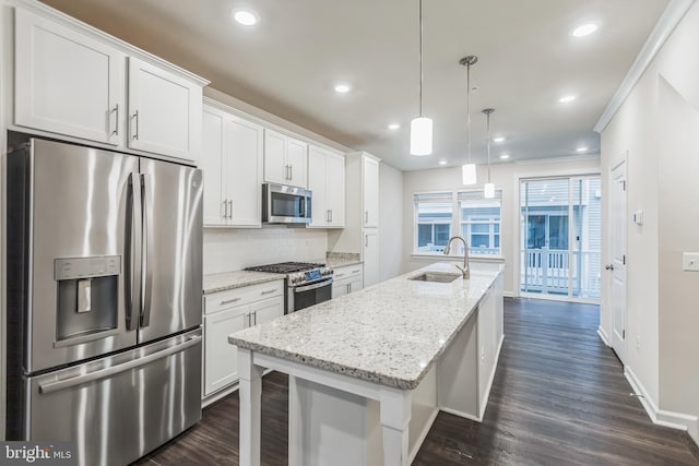 kitchen with appliances with stainless steel finishes, white cabinetry, an island with sink, backsplash, and pendant lighting