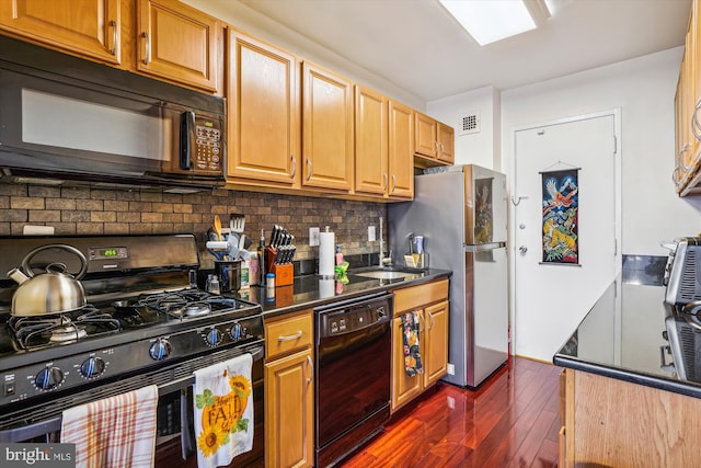 kitchen with dark wood-type flooring, decorative backsplash, black appliances, and sink