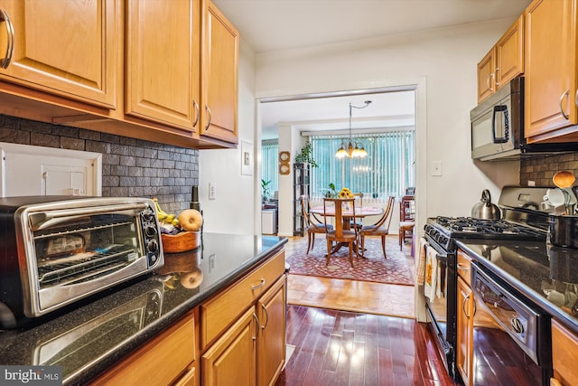 kitchen featuring pendant lighting, backsplash, black appliances, dark hardwood / wood-style floors, and a notable chandelier