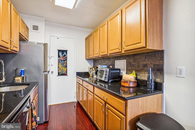 kitchen featuring sink, stainless steel dishwasher, dark hardwood / wood-style floors, dark stone counters, and decorative backsplash