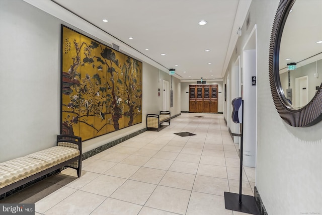 corridor with light tile patterned flooring and crown molding