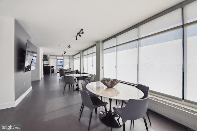 dining room featuring radiator, floor to ceiling windows, and rail lighting