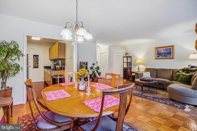 dining room featuring a chandelier and light parquet flooring