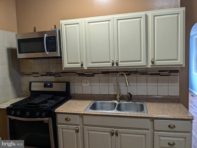 kitchen with backsplash, stainless steel appliances, white cabinetry, and sink