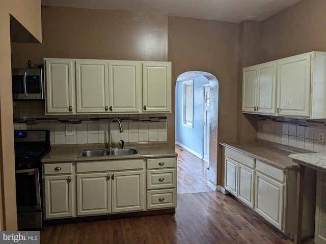 kitchen featuring backsplash, black range with electric stovetop, dark wood-type flooring, and sink