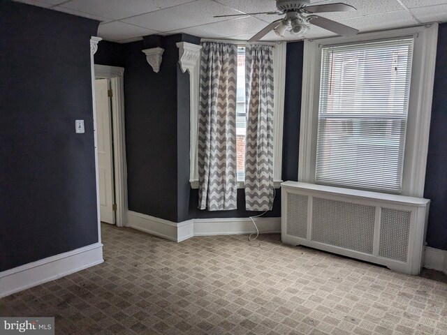 spare room with ceiling fan, radiator, and a paneled ceiling