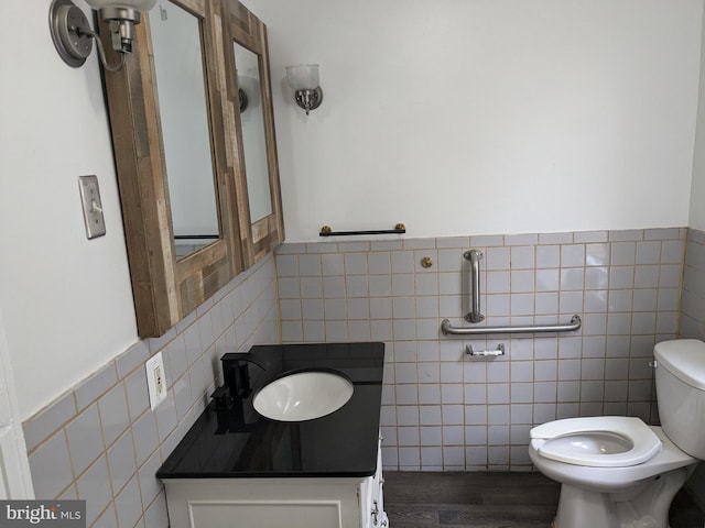 bathroom featuring tile walls, wood-type flooring, vanity, and toilet