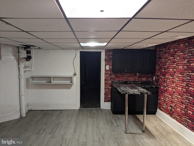 interior space featuring light hardwood / wood-style floors, brick wall, and a paneled ceiling