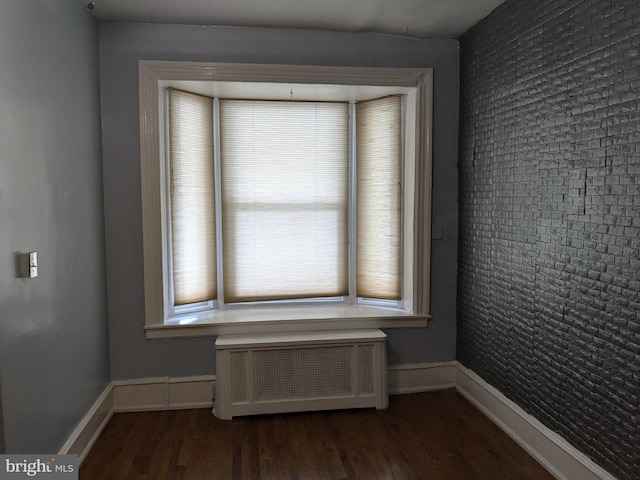 unfurnished room with radiator heating unit and dark wood-type flooring