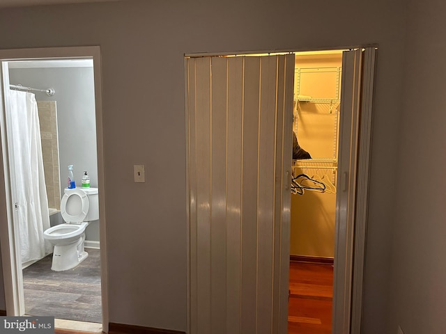 interior space with shower / bath combination with curtain, wood-type flooring, and toilet