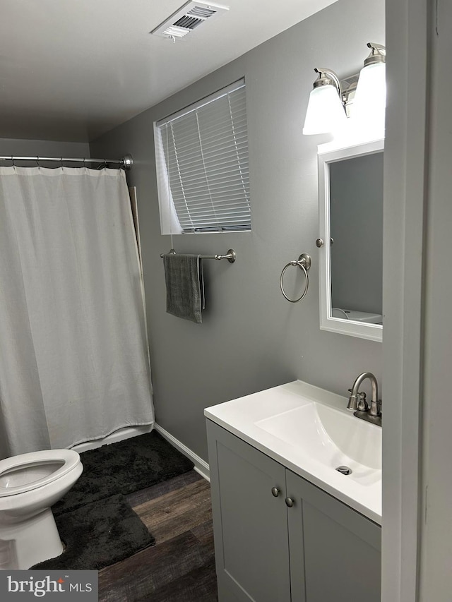 bathroom with wood-type flooring, walk in shower, vanity, and toilet