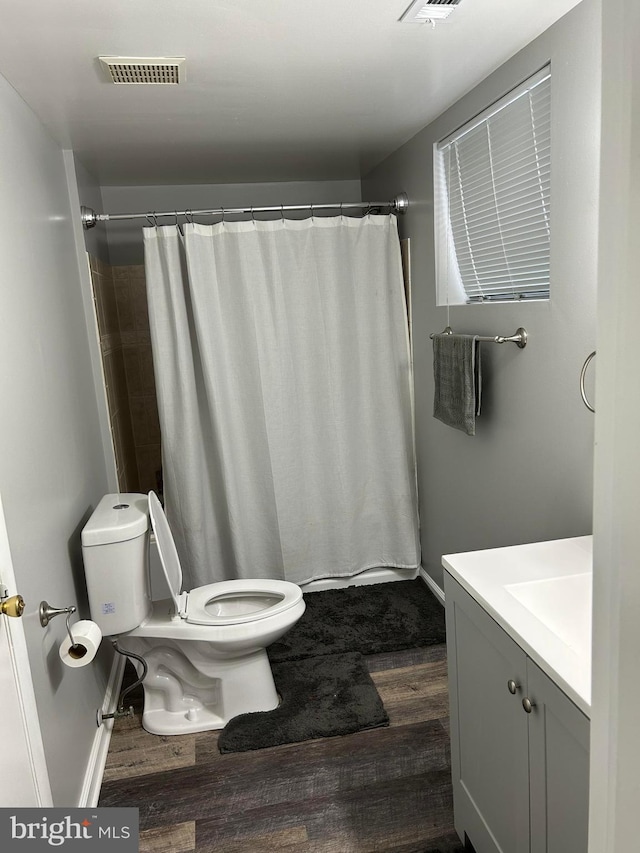 bathroom featuring vanity, hardwood / wood-style flooring, walk in shower, and toilet