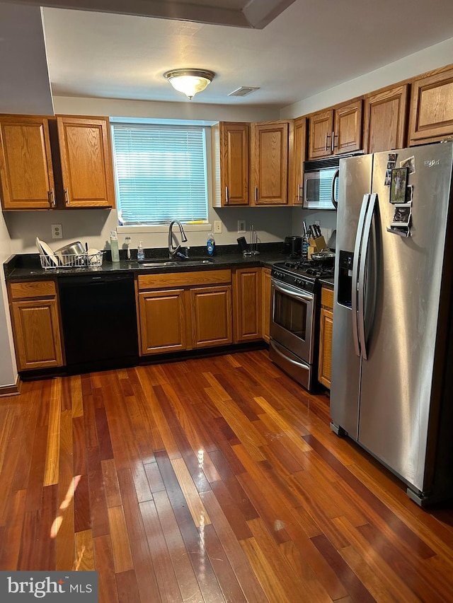 kitchen featuring appliances with stainless steel finishes, sink, and dark hardwood / wood-style flooring