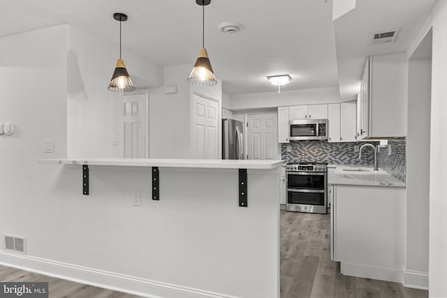 kitchen featuring appliances with stainless steel finishes, light hardwood / wood-style floors, white cabinetry, and a breakfast bar area