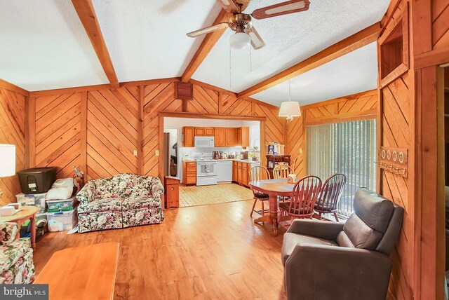 living room featuring ceiling fan, a textured ceiling, light wood-type flooring, wood walls, and lofted ceiling with beams