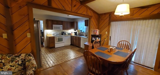 dining area featuring wood walls, sink, and dark hardwood / wood-style floors