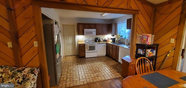 kitchen featuring tasteful backsplash, dark hardwood / wood-style floors, sink, wooden walls, and white appliances