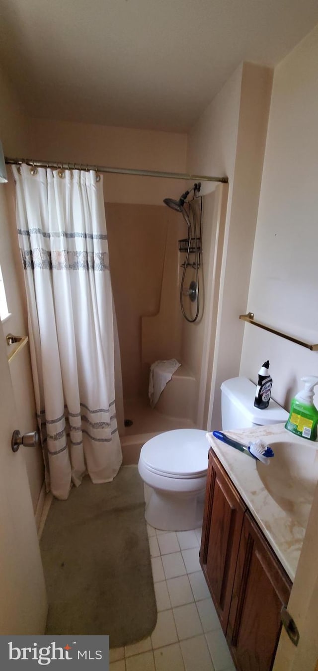 bathroom with vanity, tile patterned floors, toilet, and walk in shower