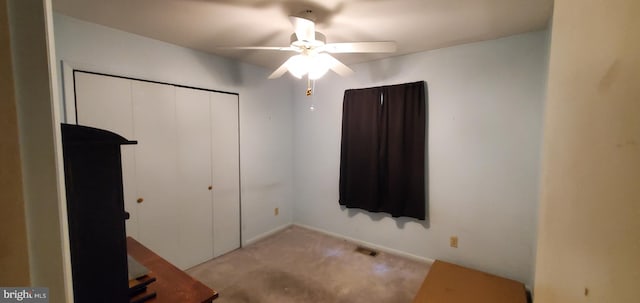 unfurnished bedroom featuring a closet, light colored carpet, and ceiling fan