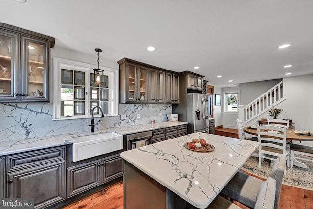 kitchen featuring a kitchen island, stainless steel appliances, sink, dark brown cabinetry, and decorative light fixtures