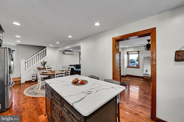 kitchen with dark hardwood / wood-style flooring, dark brown cabinetry, a center island, and stainless steel refrigerator