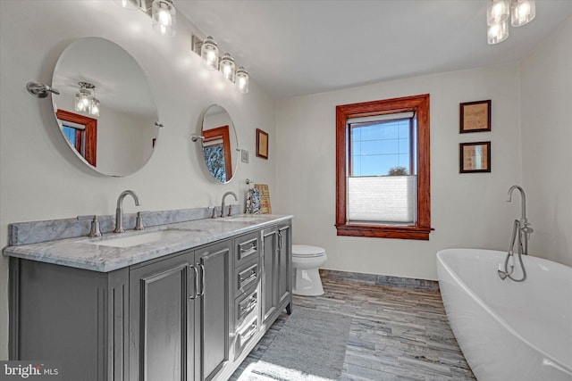 bathroom featuring toilet, hardwood / wood-style floors, vanity, and a washtub