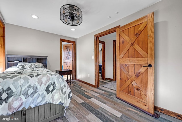 bedroom with a barn door and hardwood / wood-style floors