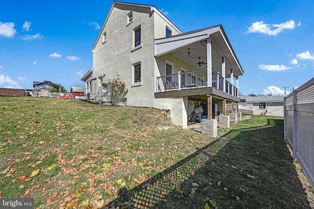 back of house featuring a lawn and ceiling fan