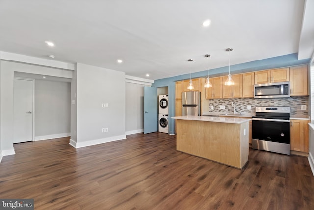 kitchen with a kitchen island, stacked washer / dryer, stainless steel appliances, pendant lighting, and dark hardwood / wood-style floors